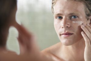 man moisturizing face